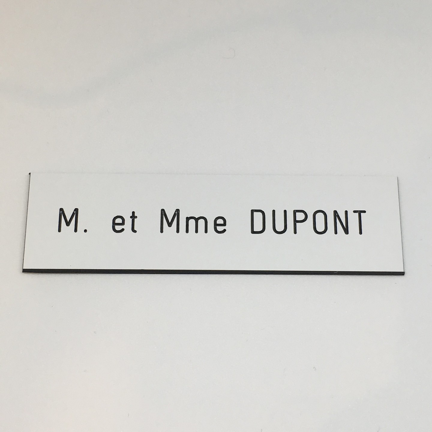 Plaque de boîte aux lettres, fond blanc, texte gravé noir