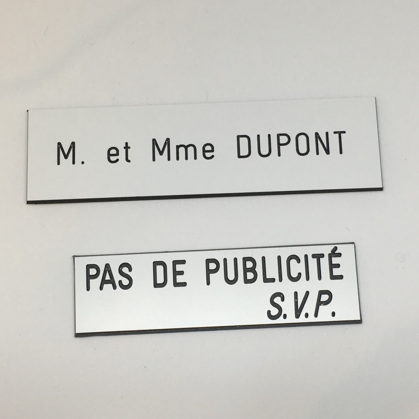 Plaque de boîte aux lettres, fond blanc, texte gravé noir